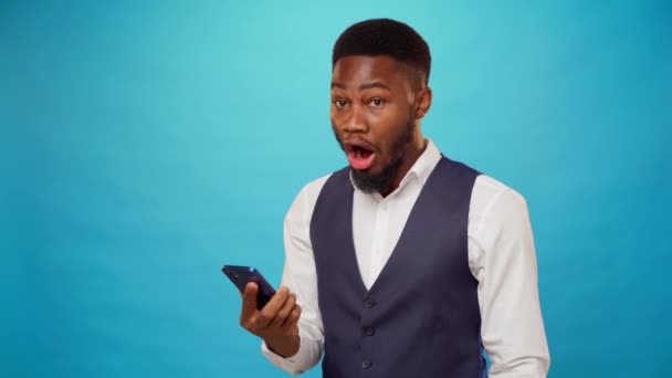 Έκπληκτος μαύρος που διαβάζει ένα μήνυμα στο κινητό του. — Αρχείο Βίντεο