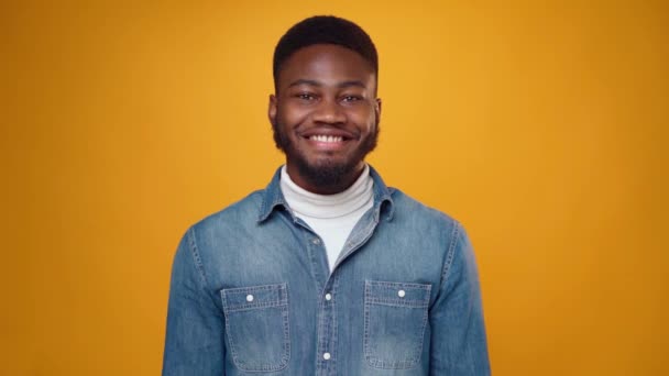 Sorprendido joven africano mostrando pulgares hacia arriba contra fondo amarillo en el estudio — Vídeos de Stock