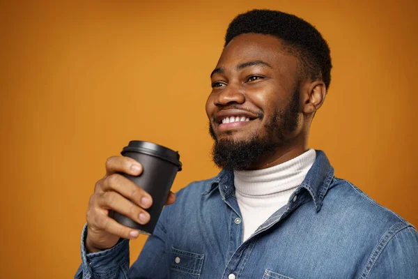 Genç Afro-Amerikalı adam sarı arka planda kahvesini yudumluyor. — Stok fotoğraf