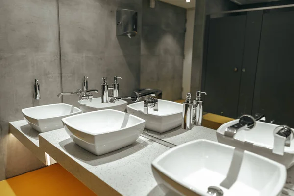 Publiczna toaleta z trzema umywalkami i lustrem — Zdjęcie stockowe