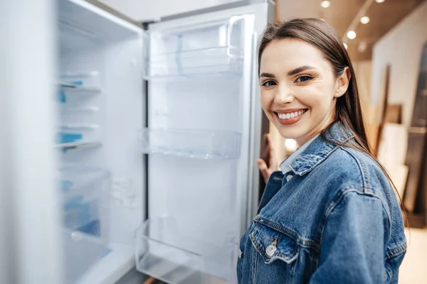 Jonge aantrekkelijke vrouw kiezen koelkast in hypermarkt — Stockfoto
