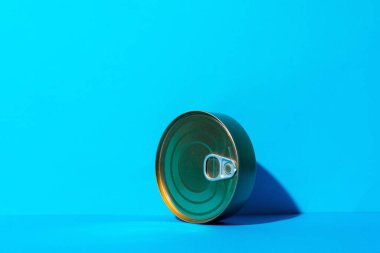 Mavi arka planda yemek olan teneke kutu.