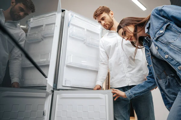 Mladý pár vybírá novou chladničku v obchodě s domácími spotřebiči — Stock fotografie