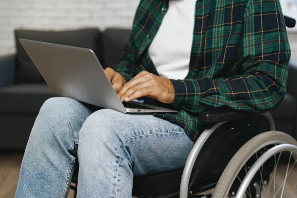 Hombre discapacitado sentado en una silla de ruedas y usando un portátil — Foto de Stock