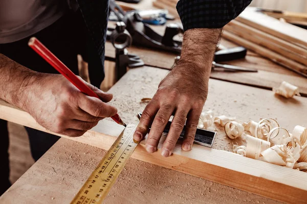 Ο ξυλουργός κάνει σημάδια από μολύβι σε μια ξύλινη σανίδα. — Φωτογραφία Αρχείου