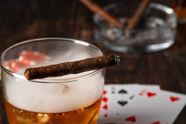 Küba purosu, viski bardağı ve cipsler masada.