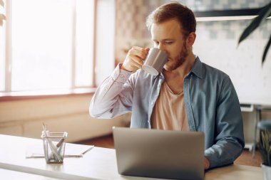 Ofiste bilgisayarla çalışan genç bir işadamı.