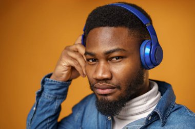 Yakışıklı Afrikalı Amerikalı adam mavi kulaklıklı müzik dinliyor.