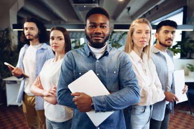 Ofiste sırada bekleyen beş farklı genç meslektaşın grup portresi.