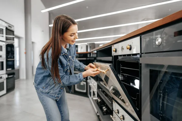 Ung kvinna letar efter ny elektrisk ugn i ett köpcentrum — Stockfoto