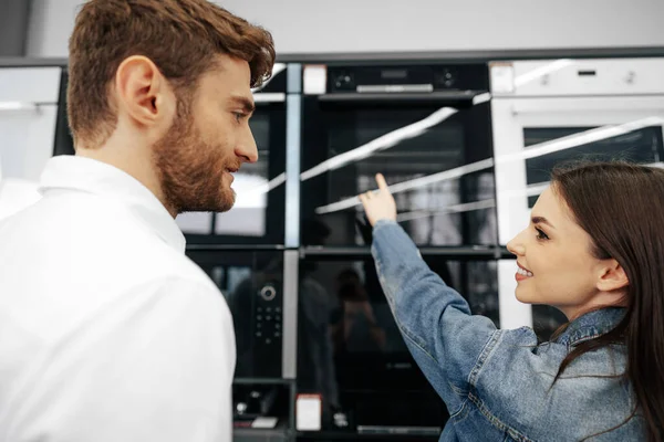 Unga par väljer ny elektrisk ugn i stormarknad — Stockfoto