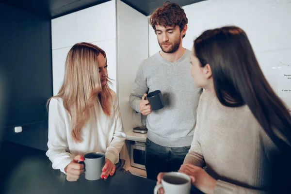 Jóvenes empresarios colegas tomando un café en la oficina, bebiendo y hablando — Foto de Stock