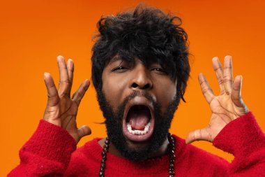 Heyecanlı genç siyah adam sarı arka planda çığlık atıyor.