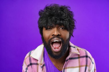 Genç heyecanlı siyah adam mor arka planda çığlık atıyor.