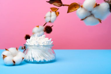 Pembe ve mavi arka planda kulakları temizlemek için pamuk tomurcukları