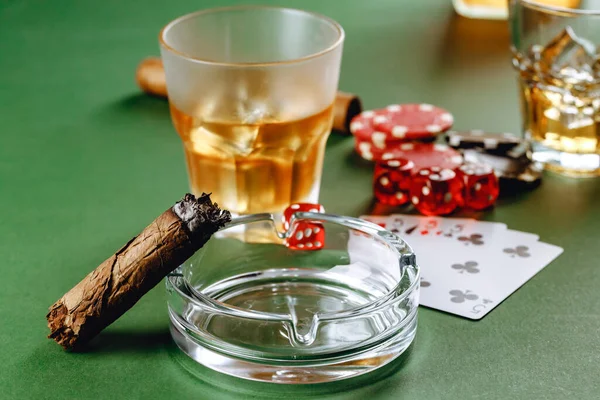 Copo de whisky charuto jogando cartas e fichas no verde