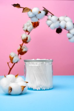 Pembe ve mavi arka planda kulakları temizlemek için pamuk tomurcukları
