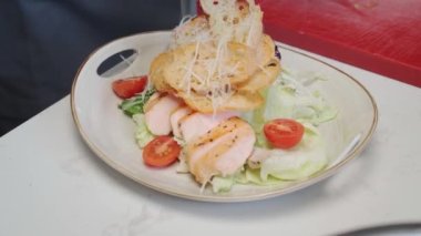 Şef ızgara tavuklu Sezar salatası pişiriyor.