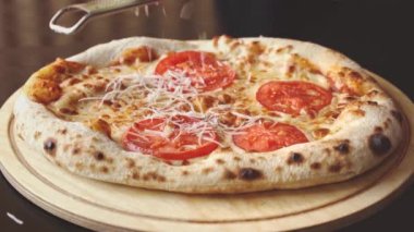 Şef yeni pişmiş pizzada peynir rendeliyor.