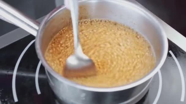 Chef revuelve cereales hirviendo en una sartén en la cocina del restaurante — Vídeos de Stock