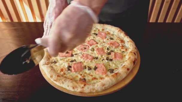 Şef yeni yapılmış pizzayı yuvarlak kesiciyle kesiyor. — Stok video