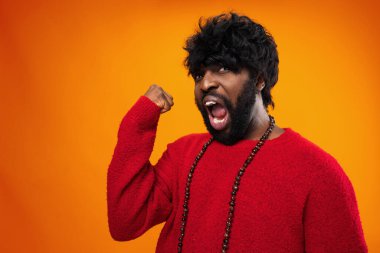 Genç heyecanlı siyah adam sarı arka planda çığlık atıyor.