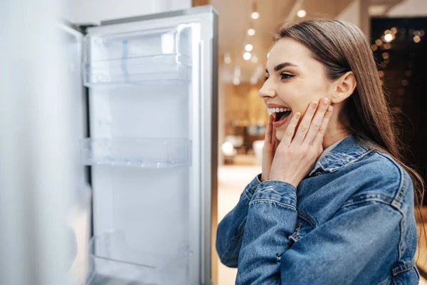 Jovem mulher atraente escolhendo geladeira no hipermercado — Fotografia de Stock