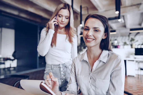 Två unga kvinnliga kollegor diskuterar affärsprojekt tillsammans på kontoret — Stockfoto