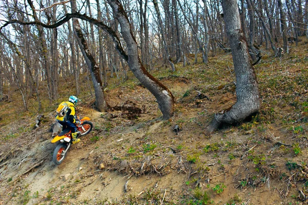 Homem em equipamento desportivo montando uma moto em montanhas — Fotografia de Stock