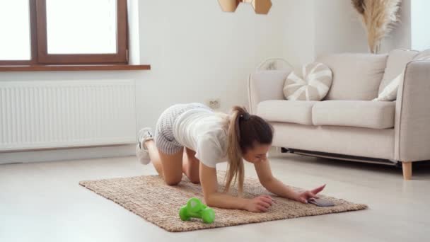 Jonge gezonde blanke vrouw workout thuis, doet plank oefening op mat — Stockvideo