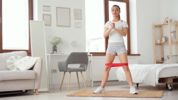 Mujer deportiva hace sentadillas en una habitación, ejercicios de fitness en casa — Vídeo de stock
