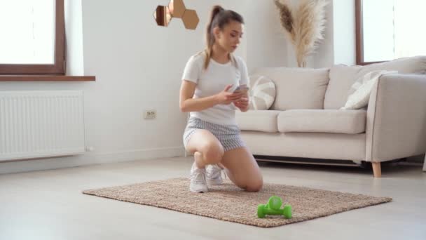 Молодая здоровая белая женщина тренировки дома, делает доску упражнения на коврик — стоковое видео
