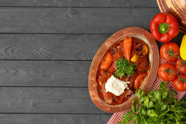 Mięso na parze z warzywami w sosie pomidorowym na drewnianym tle — Zdjęcie stockowe