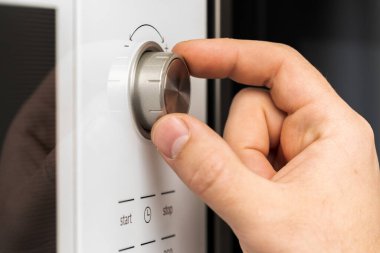 Mutfakta yemek pişirmek için mikrodalga fırının düğmesine bas.