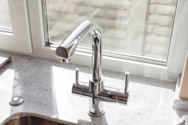 Pencerenin yanındaki mutfakta gümüş musluk var.