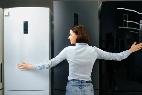 Joven mujer feliz apoyada en su nuevo refrigerador en un centro comercial — Foto de Stock