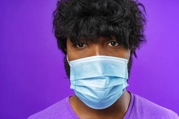 Hombre afroamericano usando mascarilla médica contra fondo púrpura —  Fotos de Stock