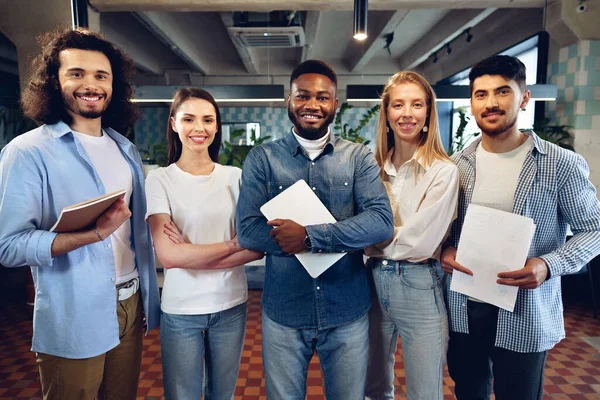 Group portrait of five diverse young colleagues standing in a row in office — Stock Photo, Image