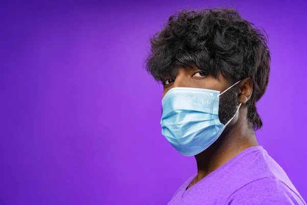 Hombre afroamericano usando mascarilla médica contra fondo púrpura —  Fotos de Stock