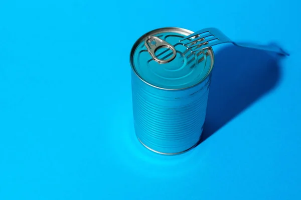 Lata de lata com comida no fundo azul — Fotografia de Stock
