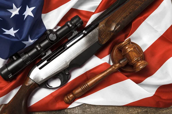 Juez de madera mazo y rifle de caza sobre bandera de EE.UU. sobre fondo de madera — Foto de Stock