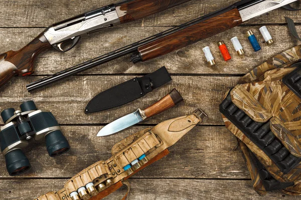 Equipo de caza sobre fondo de madera viejo incluyendo rifle, cuchillo, binoculares y cartuchos —  Fotos de Stock