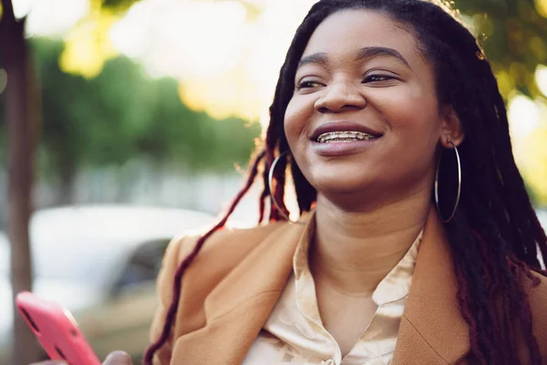 Mujer afroamericana de pie en una calle y usando un smartphone — Foto de Stock