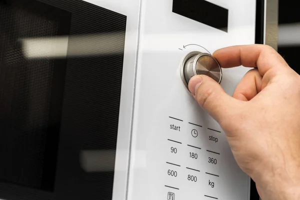 Tangan menekan tombol oven microwave untuk memasak makanan di dapur — Stok Foto