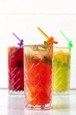 Beyaz ahşap arka planda üç farklı ferahlatıcı limonata.