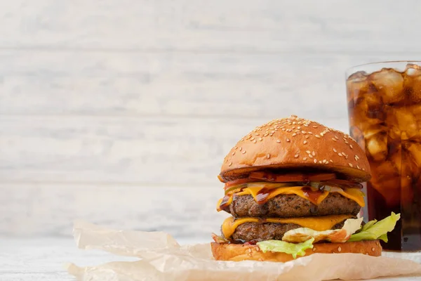 Двойной чизбургер на деревянной доске на белом размытом фоне — стоковое фото