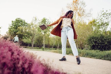 Genç Afrikalı Amerikalı kadın parkta yürüyor.