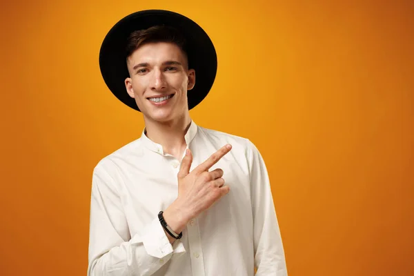 Schöner junger Mann zeigt Kopierraum vor gelbem Hintergrund — Stockfoto