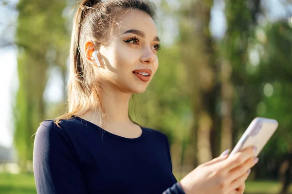 Mujer joven enciende la música para correr en su teléfono inteligente al aire libre — Foto de Stock