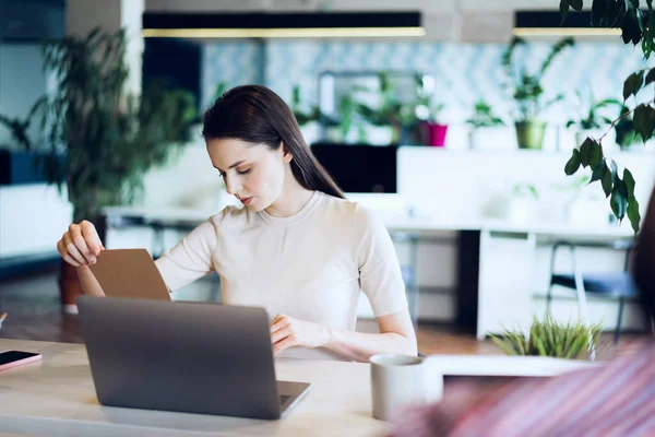 Ung attraktiv affärskvinna gör anteckningar i anteckningsblock på sin arbetsplats — Stockfoto